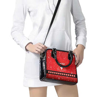 Red festive handbag with black shoulder strap and front “YOUR TEXT” logo with cross.