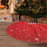 Red round tree skirt with white dots and snowflake print, laid under Christmas tree.