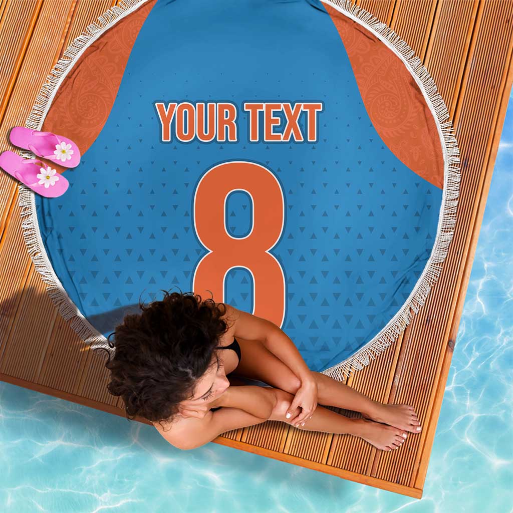 Round blue beach blanket with orange side panels and white fringe, 'YOUR TEXT' and large 8