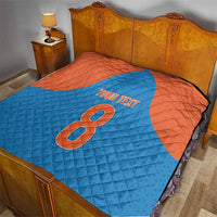 Personalized quilt on a bed in blue and orange with number 8 and “YOUR TEXT”