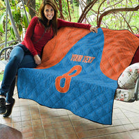 Blue and orange personalized quilt held up, showing number 8 and “YOUR TEXT”