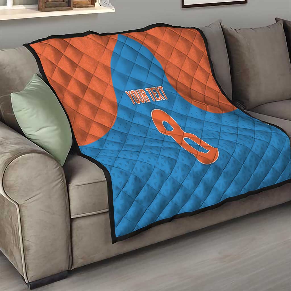 Personalized quilt draped on a sofa in blue and orange with number 8 and “YOUR TEXT”
