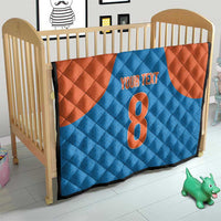 Personalized blue and orange quilt in a crib with number 8 and “YOUR TEXT”