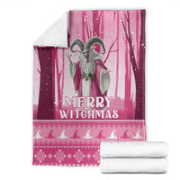 Pink Christmas witch blanket with witch illustration and 'Merry Witchmas' text, with folded rolls