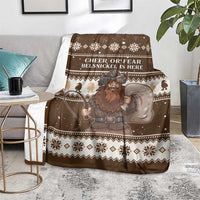 Brown Christmas Belsnickel blanket draped on chair with character graphic and snowflake trim