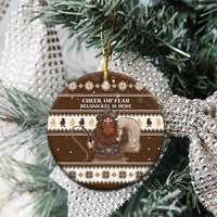 Brown ceramic circle Belsnickel ornament hanging on tree, “Cheer or Fear” text visible.