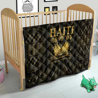 Haiti 1804 quilt on crib, dark quilt with gold “HAITI 1804” text and geometric trim