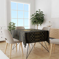 Black and gold tablecloth with geometric print pattern and checker-style border on a dining table.