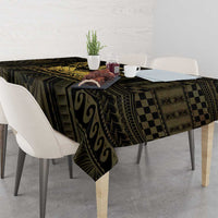 Black and gold tablecloth with abstract and checkered motifs draped over a square table.