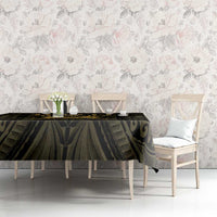 Black and gold tablecloth with ornate pattern draped on a dining table with chairs.