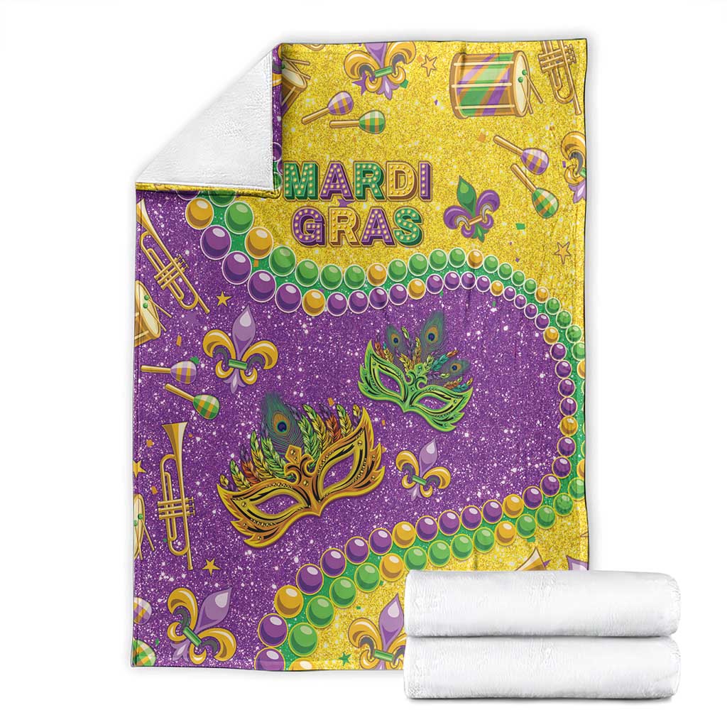 Purple and gold Mardi Gras glitter blanket, folded with masks, beads, and musical icons