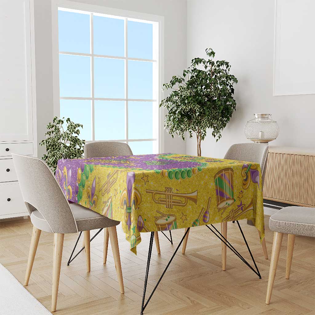 Glitter Mardi Gras tablecloth in gold and purple with green fleur-de-lis, masks, and stars.