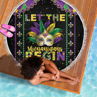 Round black Mardi Gras beach blanket with mask graphic, purple beads, and white fringed edge