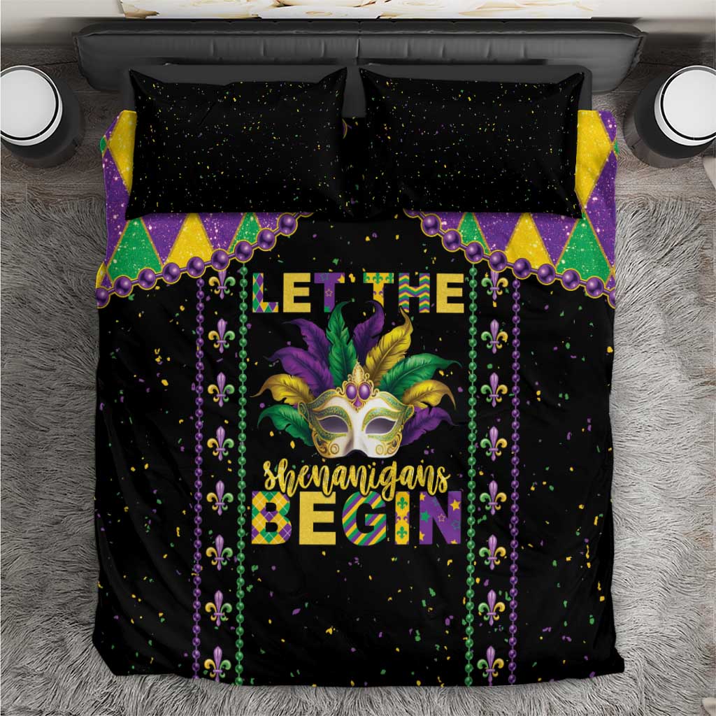 Black Mardi Gras bedding set, top view, with diamond corners, masked face art, and bright 'Begin' text