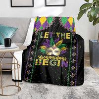 Black Mardi Gras throw blanket draped over sofa with mask, fleur-de-lis beads and text
