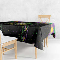 Black patterned tablecloth with purple-green fleur-de-lis motifs and confetti