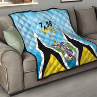 Light blue quilt blanket draped on sofa with “7 58 L•VE” and Saint Lucia coat of arms