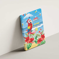 Blue canvas wall art of a Santa-hat macaw parrot with tropical flowers and beachy Christmas text