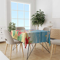 Blue tropical Christmas tablecloth draped over dining table with red macaw and leaves