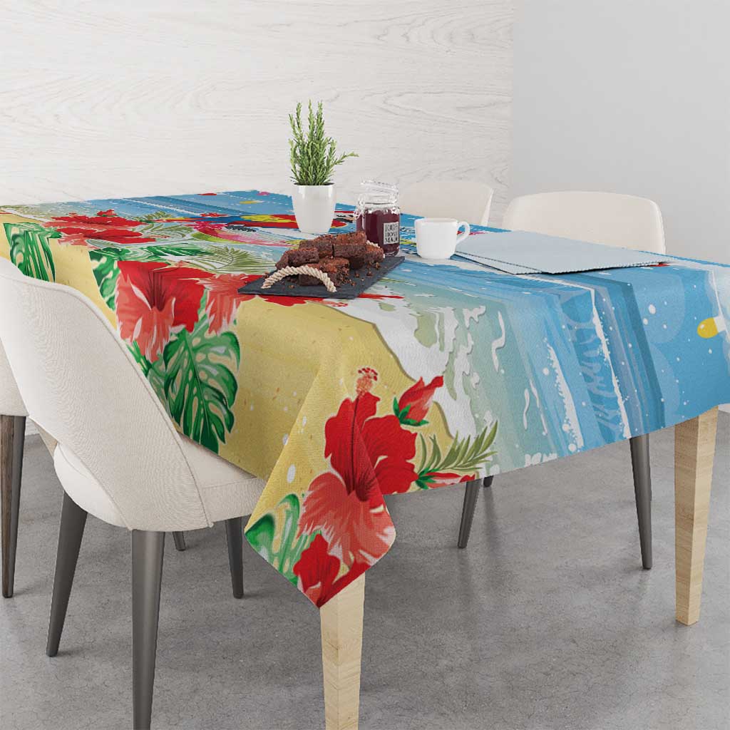 Blue tropical Christmas tablecloth with red flowers, green palm leaves, and macaw