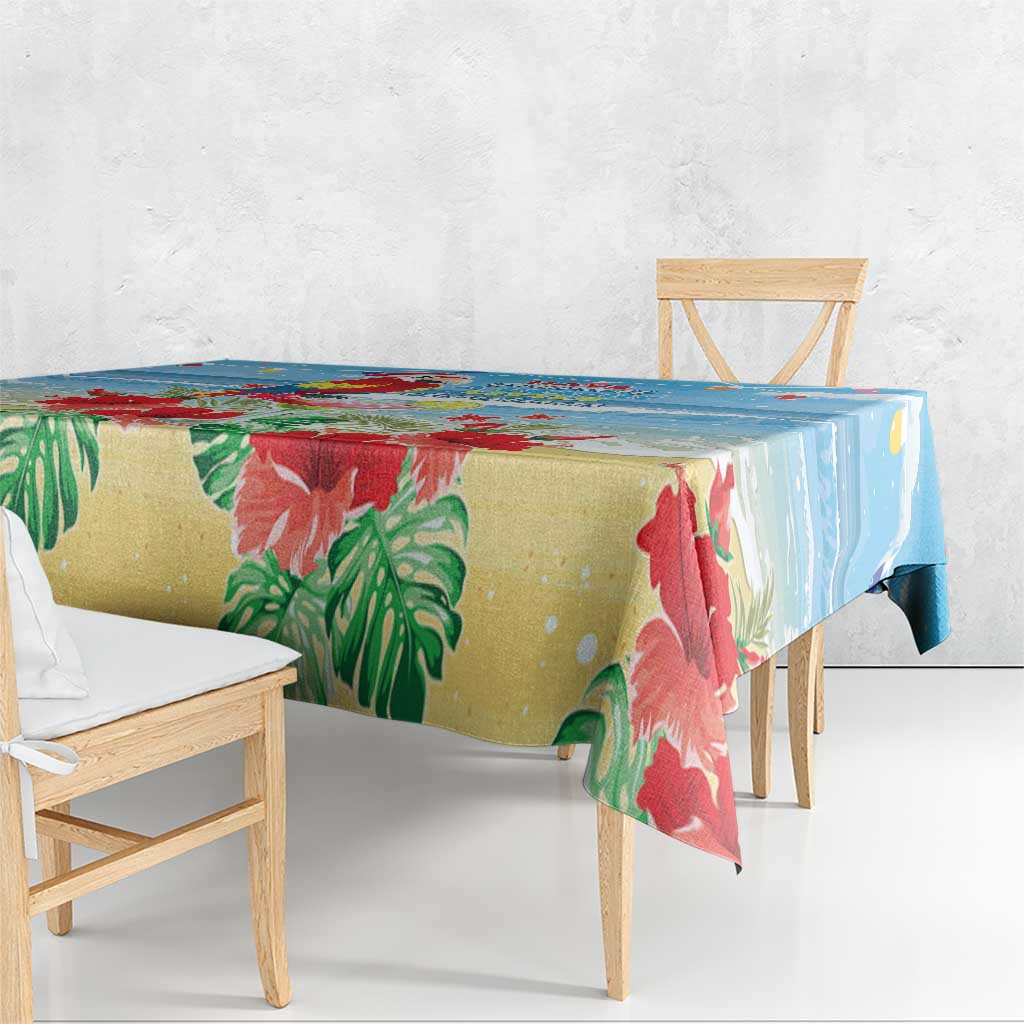 Blue tropical Christmas tablecloth corner with red floral print and green palm leaves