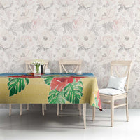 Blue tropical Christmas tablecloth with red flowers and green palm leaves on dining table