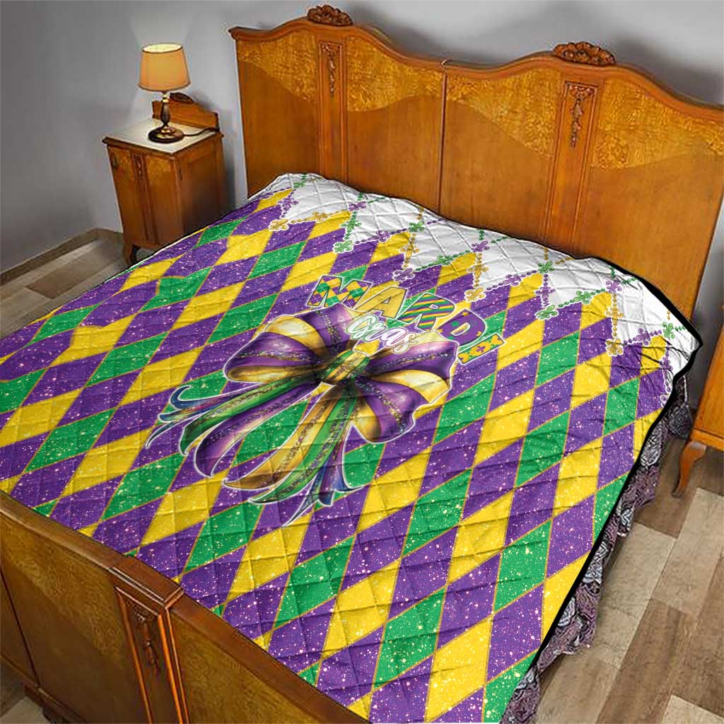 Colorful diamond-pattern quilt with large multicolor bow on a bed