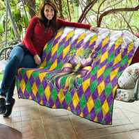 Colorful diamond-pattern quilt with large multicolor bow, draped over a chair
