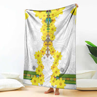 White throw blanket spread out, featuring long yellow floral garland and green hem