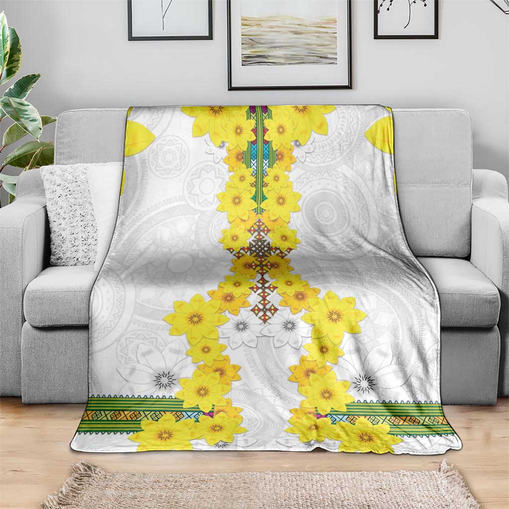 White blanket draped with yellow flower centerpiece over gray swirl motifs and green trim