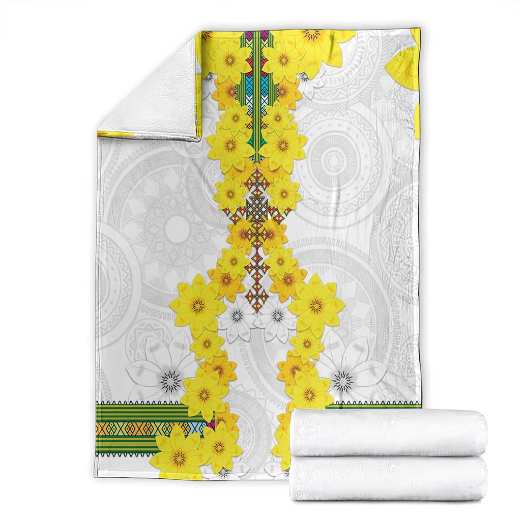 White blanket with bright yellow flower garland motif and green patterned trim