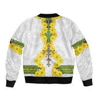 White bomber jacket with yellow floral tile center panel, green-trim bands, black ribbed hem