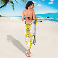 White sarong with yellow floral center panel and green-trimmed hem border, trailing.