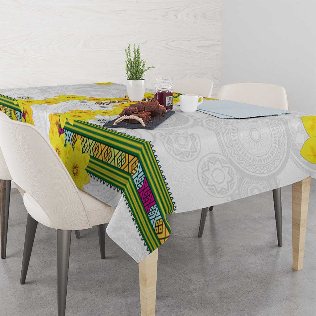 White tablecloth with yellow flowers and green banded border, draped over table