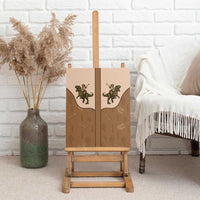 Retro western canvas wall art with cowboy and green dinosaur graphic, on wooden easel