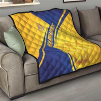 Barbados quilt blanket draped over sofa, gold and blue diagonal design with emblem