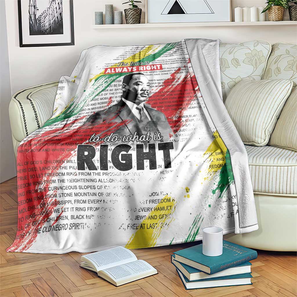 White MLK tribute blanket with multicolor splatter text and portrait, draped on couch