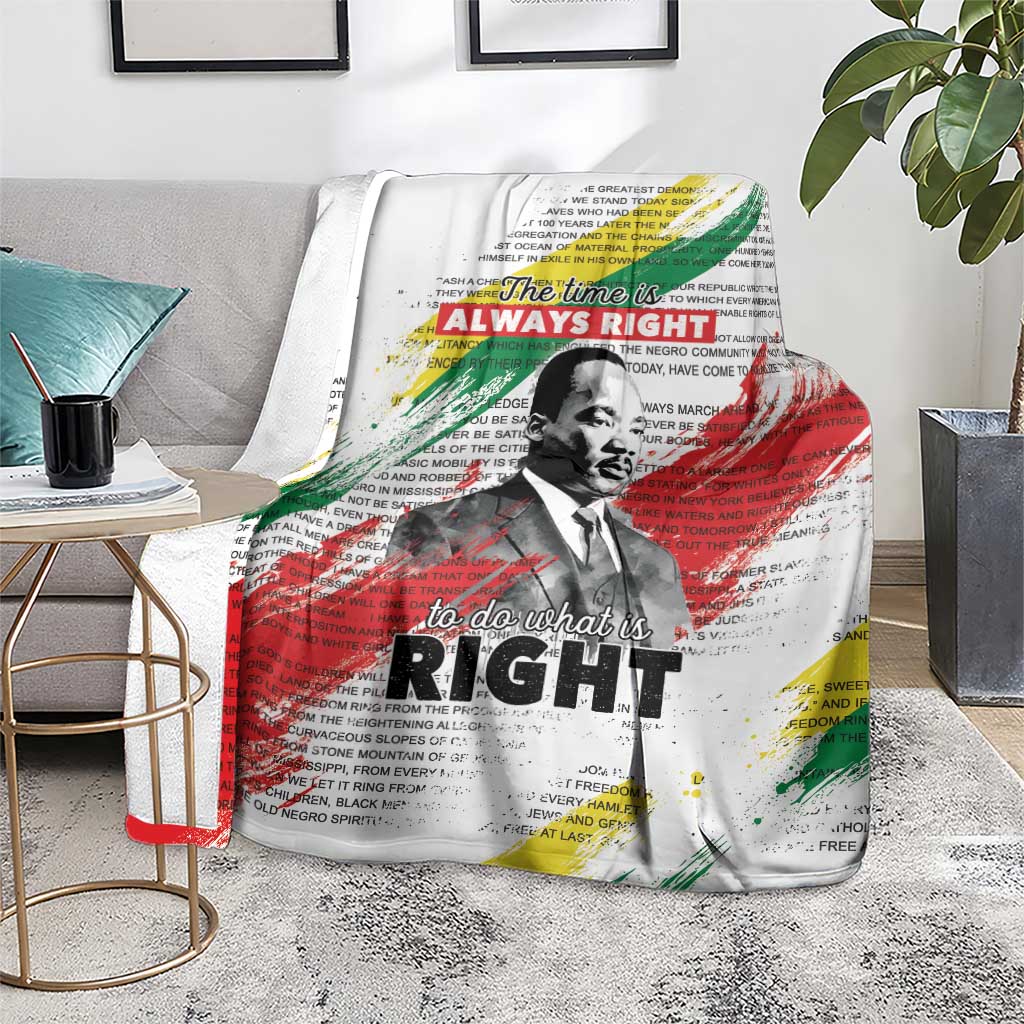 White MLK tribute blanket with portrait and colorful text accents, on gray bedding