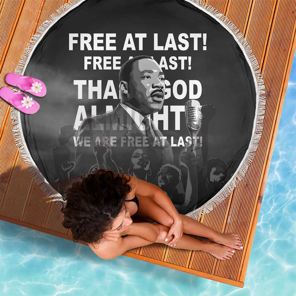 Circular black beach blanket with white tassel fringe, MLK portrait and “Free at last”