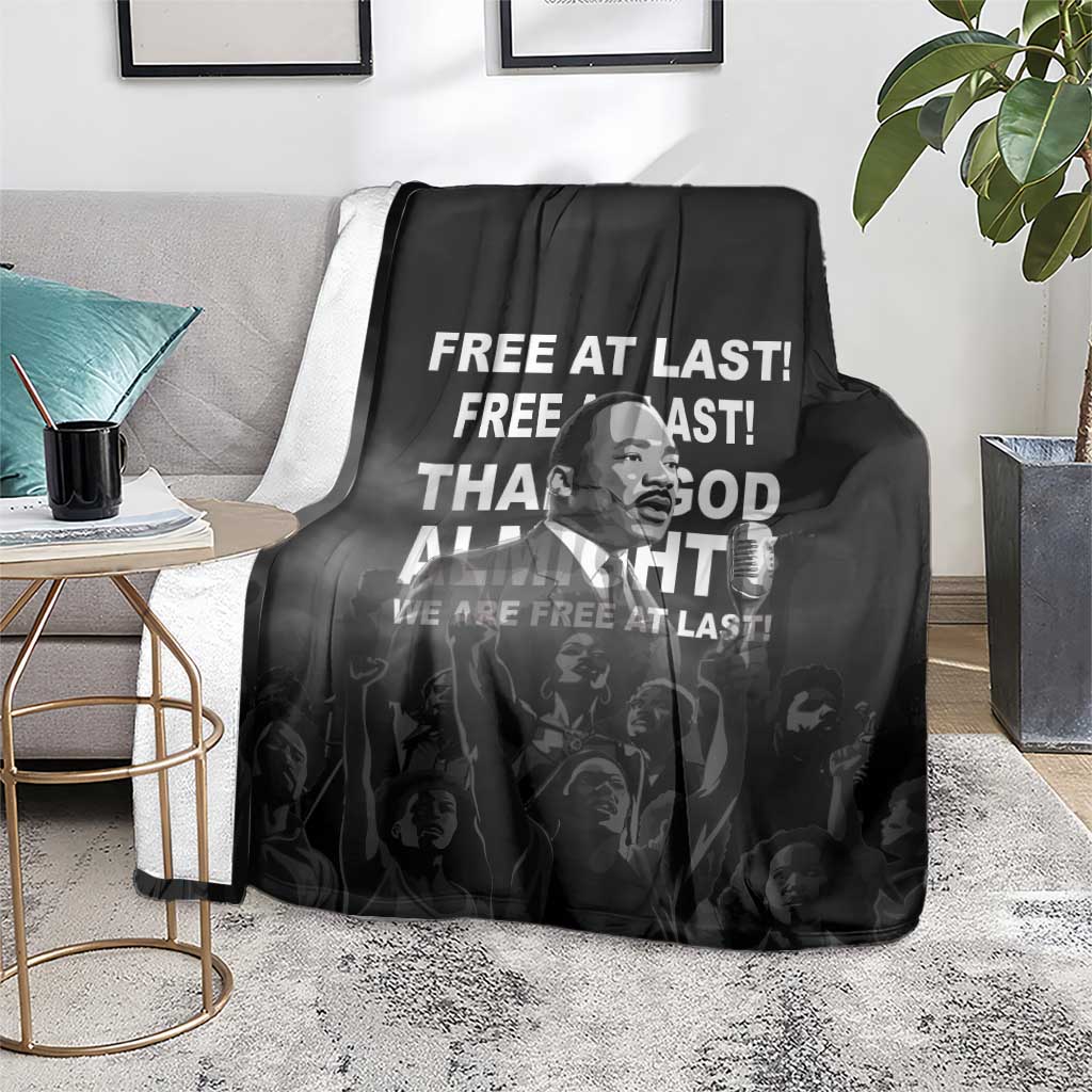 Black MLK portrait blanket with bold white text, folded on living room rug