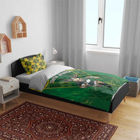 Green bedding set on a bed with South Africa text, yellow pattern, and antelope mascot.