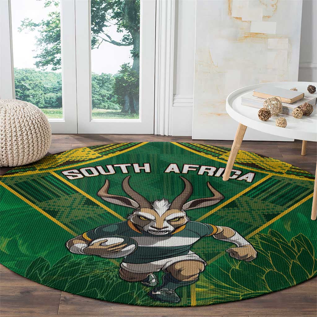 Round green rug with yellow border, South Africa text and antelope mascot in grass
