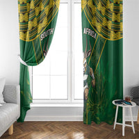 Green window curtains with gold pattern and antelope mascot, hung on window