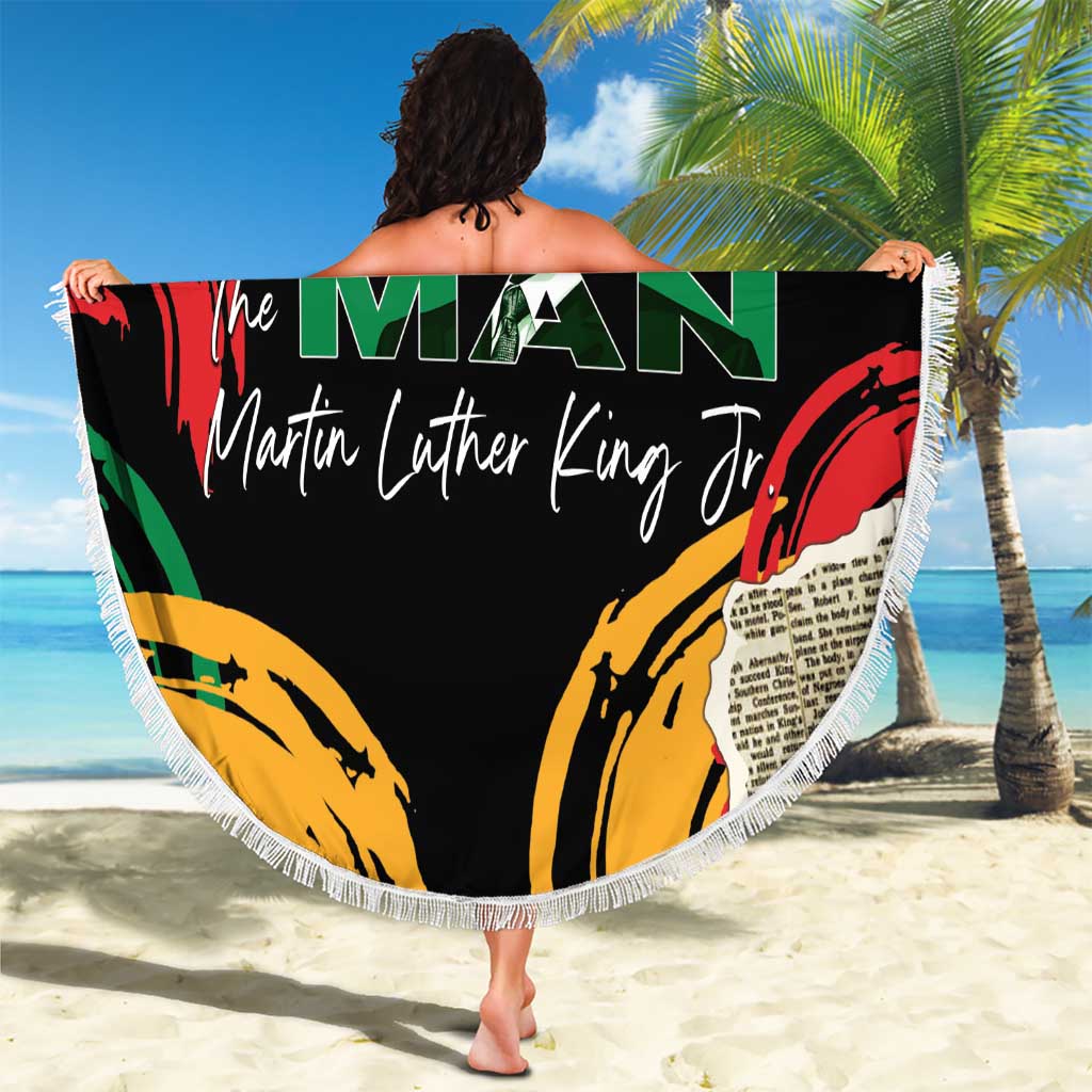 Black round beach blanket with fringe held up outdoors, “The Man” and MLK Jr print