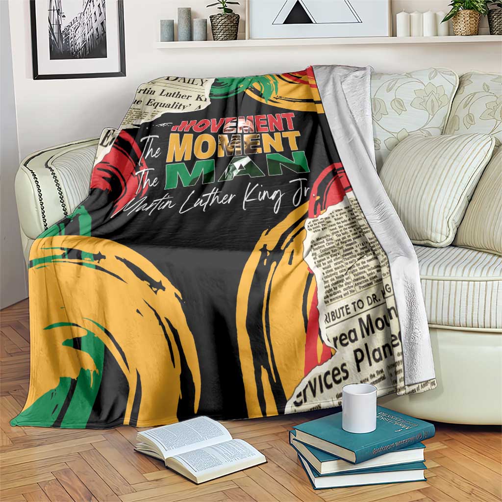 Black MLK legacy blanket with colorful fist artwork and 'The Movement Man' text, on sofa