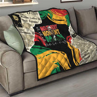 Black quilt with multicolor graphic print and quilted stitching, draped on sofa