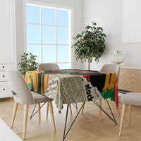 Rectangular tablecloth with black, yellow, red, and green print over dining table.