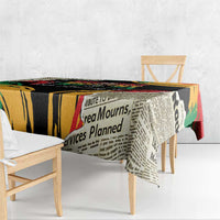 Black tablecloth with bold typography in yellow, red, and green, draped on dining table.