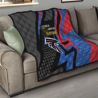 Black quilt blanket on gray couch with Antigua and Barbuda Falcons crest and blue/red diagonals
