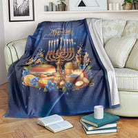 Blue Hanukkah blanket with menorah and 'Happy Hanukkah' graphic, draped on couch.